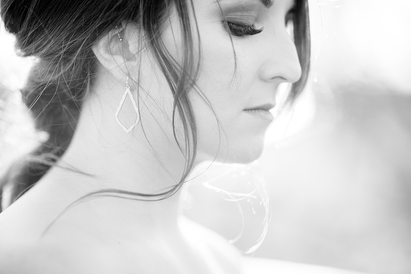 soft black and white of bride looking downward with Kendra Scott earrings